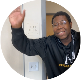 Man with a black sweater and glasses waving his hand.