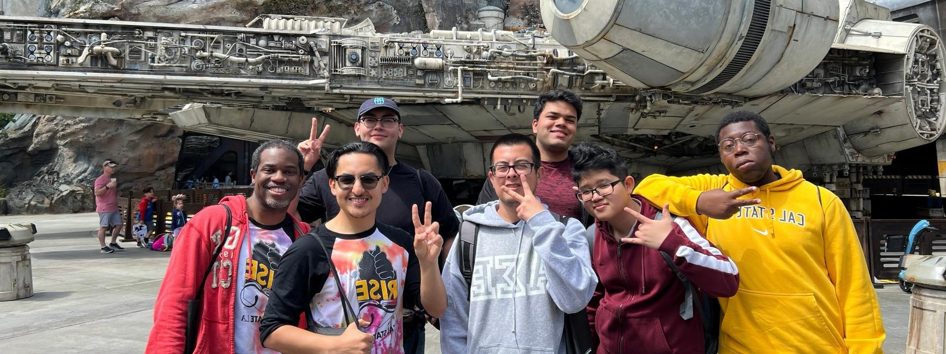 Seven men smiling in front of a mechanic ship.